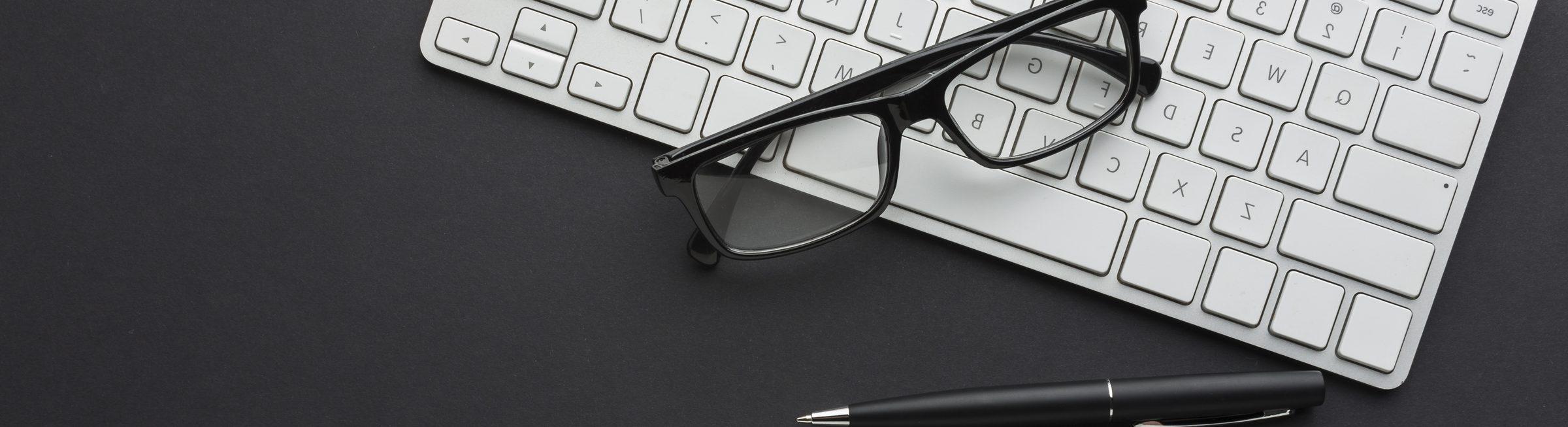 Un clavier, des lunettes et un stylo à bille